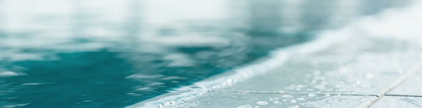 Bordo vasca e acqua calma di una piscina Ondarte in Ticino